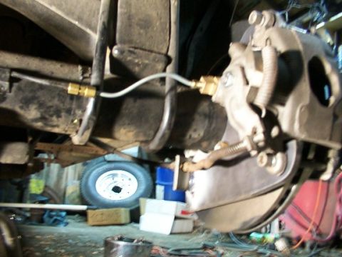 1995 Ford C-350 (Centurion Conversions) - Close-up view of a vehicle's disc brake assembly, showing the caliper, rotor, and brake line.