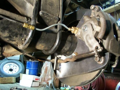 1995 Ford C-350 (Centurion Conversions) - Underside view of a vehicle's brake system, showing the caliper, rotor, and suspension linkage.