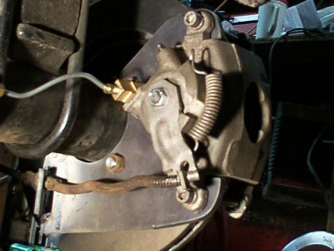 1995 Ford C-350 (Centurion Conversions) - A close-up view of a vehicle's brake caliper assembly, showing the brake line and spring mechanism.