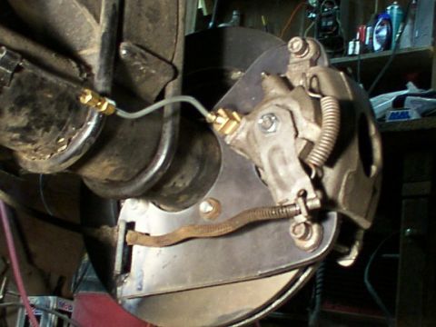 1995 Ford C-350 (Centurion Conversions) - Close-up view of a vehicle's disc brake caliper and rotor assembly, showing the brake line connection.