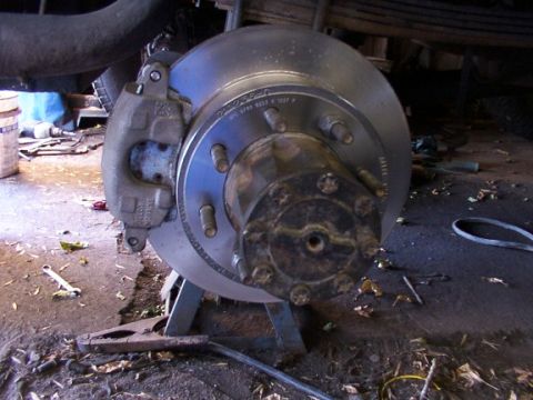 1995 Ford C-350 (Centurion Conversions) - Close-up of a vehicle's brake rotor and caliper assembly, supported by a jack stand.