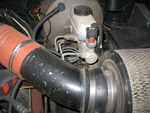 1995 Ford C-350 (Centurion Conversions) - Close-up view of engine components, focusing on the brake master cylinder and air intake hose.