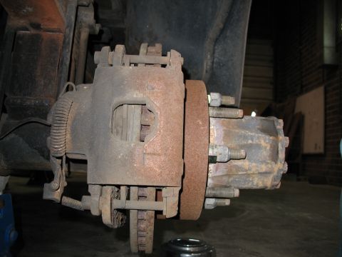 1995 Ford C-350 (Centurion Conversions) - Close-up view of a heavily rusted brake caliper and rotor, likely from a truck or heavy equipment.