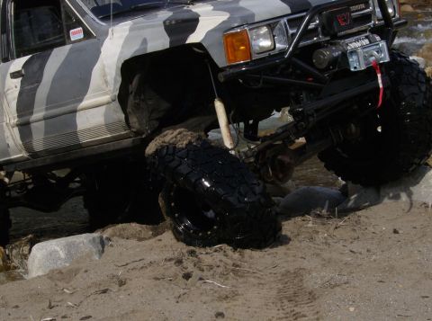 1986 Ford Bronco - This lifted Toyota 4Runner, likely a 1989 model, is shown off-roading with its tires on rocks and sand.
