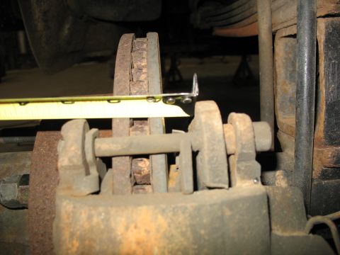 1995 Ford C-350 (Centurion Conversions) - A tape measure is used to inspect a worn brake rotor and caliper assembly.