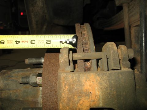 1995 Ford C-350 (Centurion Conversions) - A tape measure is used to check the thickness of a worn brake rotor on a vehicle's braking system.