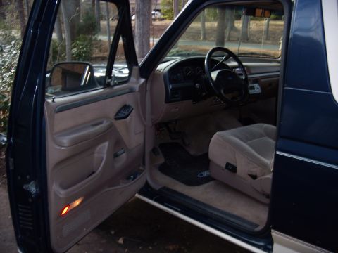 1992 Ford Bronco - Interior view of a 1992 Ford Bronco with the driver's door open, showing the tan seats and dashboard.