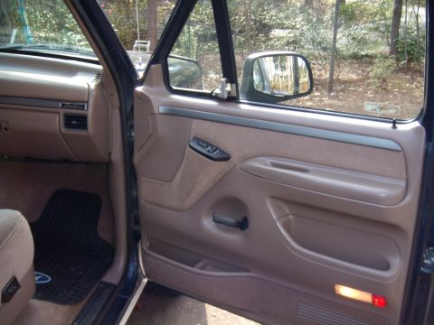 1992 Ford Bronco - Interior view of a 1992 Ford Bronco, showing the door panel, dashboard, and floor mat.