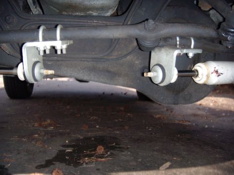 1992 Ford Bronco - Close-up view of the steering linkage and shock absorber mounted to the vehicle's undercarriage.
