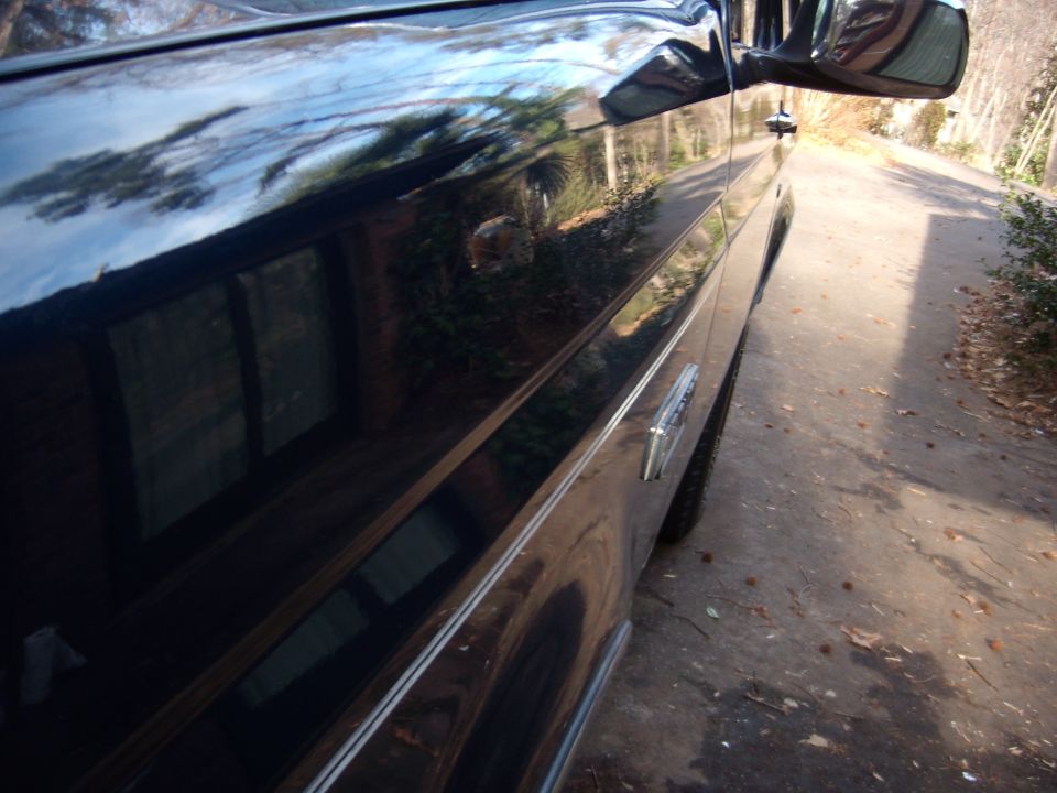 Side view of a 1992 Ford Bronco with chrome trim and a reflection of trees in the paint