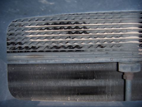 1992 Ford Bronco - Close-up view of a vehicle's radiator and condenser fins, showing signs of fluid leaks.