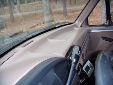 1992 Ford Bronco - The dashboard of a vehicle is shown from the passenger's perspective, with trees visible through the windshield.