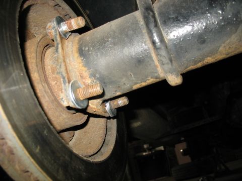 1995 Ford C-350 (Centurion Conversions) - Close-up view of a rusty rear axle brake assembly, showing the rotor and mounting bolts.