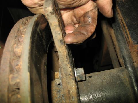 1995 Ford C-350 (Centurion Conversions) - A mechanic's dirty hand inspects a worn brake rotor and caliper, highlighting the need for maintenance.