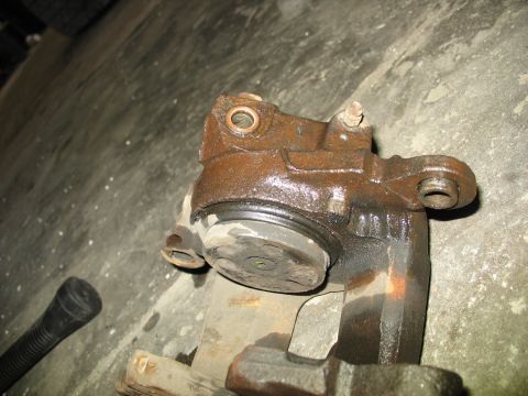 1995 Ford C-350 (Centurion Conversions) - A close-up view of a rusty brake caliper, likely a replacement part, against a concrete background.
