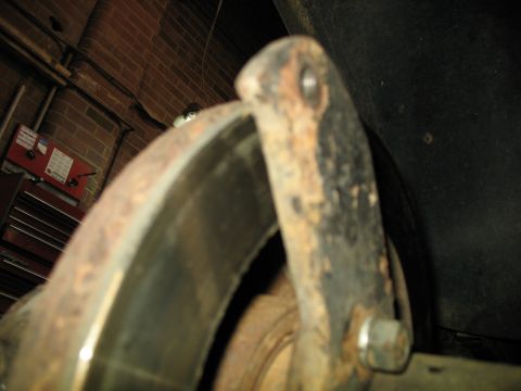 1995 Ford C-350 (Centurion Conversions) - This is a close-up view of a rusty brake rotor and caliper bracket, likely from a vehicle in a garage.