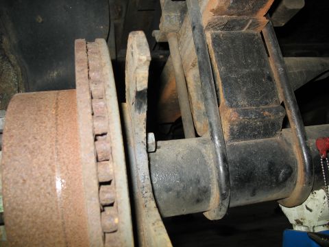 1995 Ford C-350 (Centurion Conversions) - Close-up view of a rear disc brake assembly, showing the rotor and leaf spring suspension components.