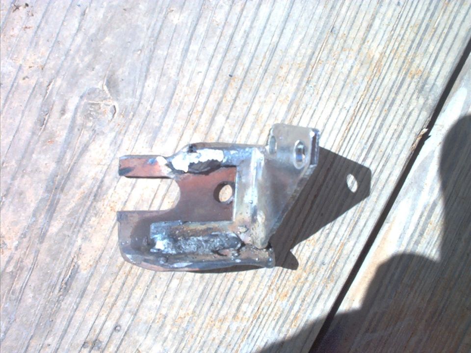 Fabricated welded steel mounting bracket with bolt holes lying on a wood deck