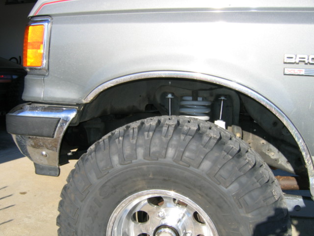 1989 Ford Bronco front fender, chrome bumper trim, and large off-road tire