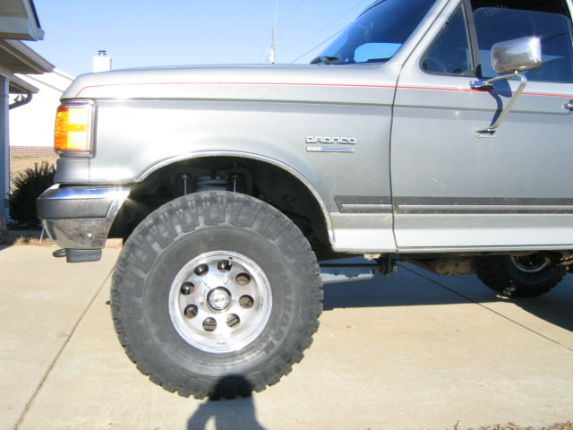 Silver Ford Bronco with red pinstripes, lifted suspension, and large tires