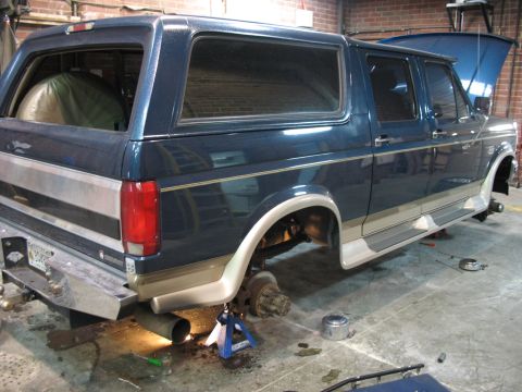 1995 Ford C-350 (Centurion Conversions) - This blue conversion van is shown from the rear with its wheels removed and the vehicle supported by jack stands.