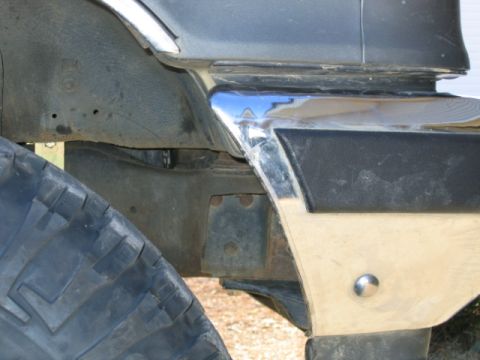 1989 Ford Bronco - Close-up of a vehicle's bumper trim and tire, with visible suspension parts.