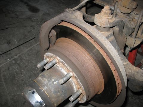 1995 Ford C-350 (Centurion Conversions) - Close-up view of a vehicle's front disc brake assembly, showing a rusty rotor and caliper.