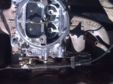 1985 Ford Bronco - Top-down view of a four-barrel carburetor mounted on an engine intake, with the choke plates and throttle bores visible along with linkage,…