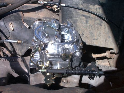 1985 Ford Bronco - A polished aftermarket Weber carburetor mounted atop an engine, viewed from above with the throttle linkage, springs and fuel line visible.…