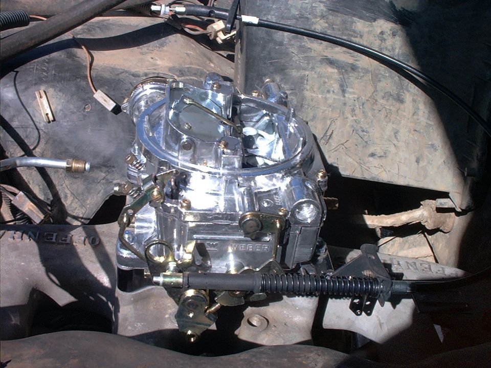 Chrome Weber carburetor installed on engine, top-down view showing linkage and springs