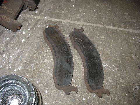 1995 Ford C-350 (Centurion Conversions) - Worn brake pads are shown on a concrete floor, possibly before replacement.