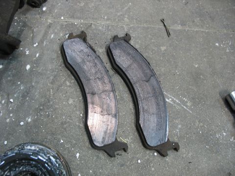 1995 Ford C-350 (Centurion Conversions) - Close-up view of two cracked brake pads, suggesting significant wear and tear.