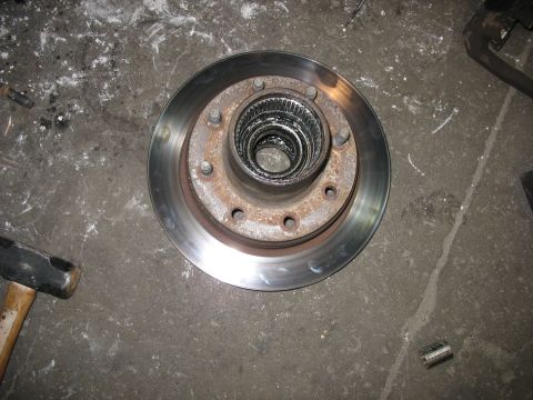 1995 Ford C-350 (Centurion Conversions) - A close-up of a vehicle's brake rotor and hub assembly, resting on a workshop floor.
