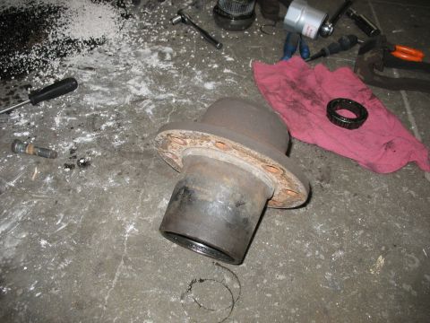 1995 Ford C-350 (Centurion Conversions) - A brake drum and bearing lie on a concrete floor amidst tools and a red rag, suggesting a repair or maintenance activity.