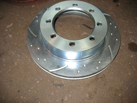 1995 Ford C-350 (Centurion Conversions) - A single, new brake rotor with drilled holes and curved slots is shown up close.
