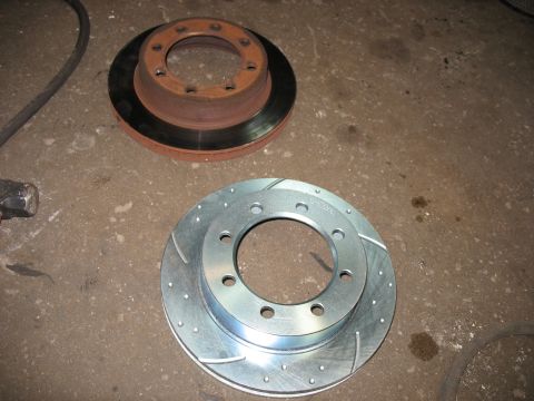 1995 Ford C-350 (Centurion Conversions) - Two brake rotors, one new and one old, are displayed on a concrete surface.