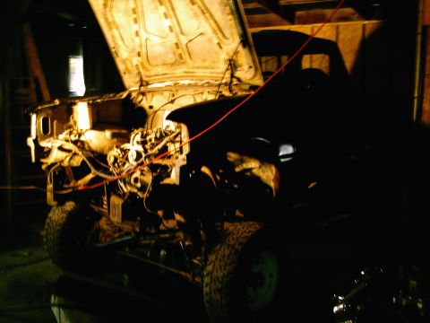 2001 Dodge 2500 - The engine bay of a truck is visible with the hood open, illuminated in a dimly lit garage.