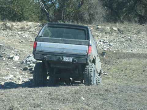1986 Ford Bronco - This lifted 1986 Ford Bronco navigates a rough, off-road terrain from a rear-facing perspective.