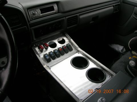 1996 Ford Bronco - Interior view of a vehicle's custom center console auxiliary switches and cup holders.