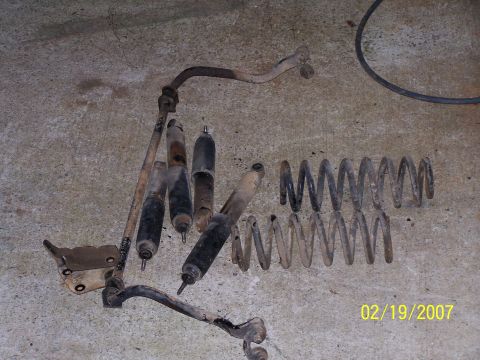 1979 Ford F-150 - A collection of worn suspension parts, including shocks and springs, lies on a concrete surface.