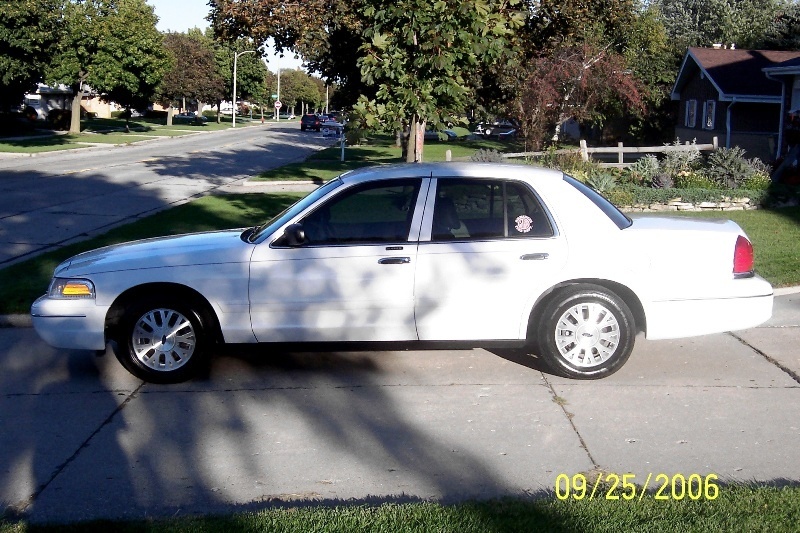 White Ford Crown Victoria sedan side profile parked in a suburban driveway