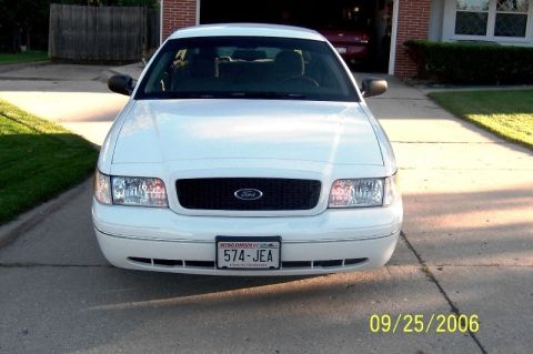 2003 Ford Crown Victoria - A white 2003 Ford Crown Victoria is parked in a driveway, facing the camera.