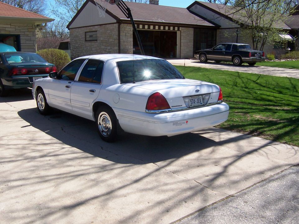 White Ford Crown Victoria parked in driveway, another car in background