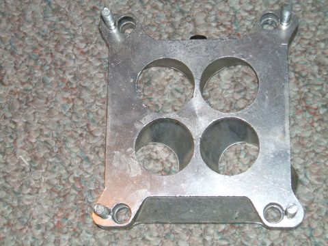 1974 Dodge Challenger - This aluminum carburetor spacer has four openings and is shown on a carpeted surface.