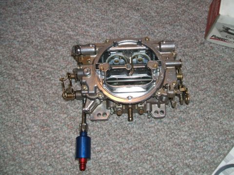 1974 Dodge Challenger - Holley carburetor with a blue fuel filter attached, resting on a carpeted surface.