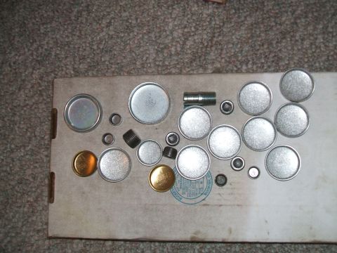 1974 Dodge Challenger - Various metal plugs and threaded fittings are laid out on a piece of cardboard.