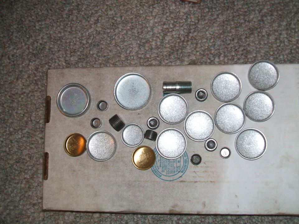 Assortment of metal plugs and threaded parts on a cardboard surface