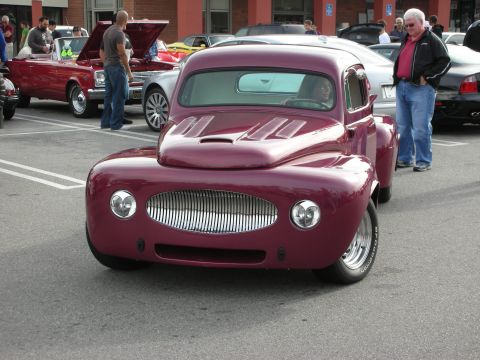 1998 Ford Crown Victoria - maroon chopped custom coupe with a wide oval grille and hood scoops faces the camera at a car show.