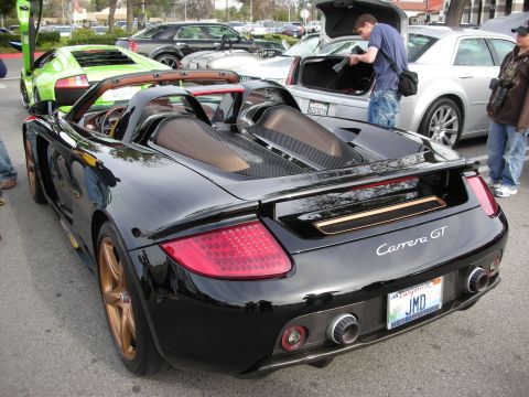 1998 Ford Crown Victoria - Rear three-quarter view of a black Porsche Carrera GT with bronze wheels, its Carrera GT badge and California plate visible.
