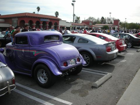 1998 Ford Crown Victoria - purple chopped three-window hot rod coupe parked next to a silver Ford Mustang in a car-show lot.